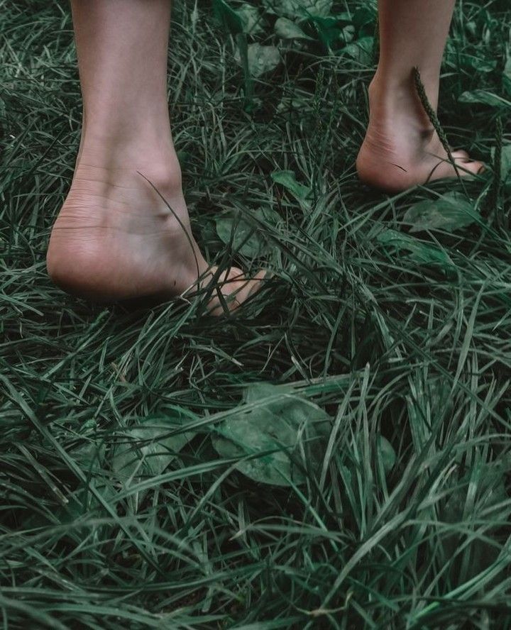 dei piedi che calpestano dell'erba verde